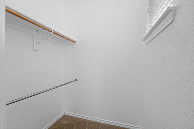 Walk in closet featuring dark colored carpet | Image 27