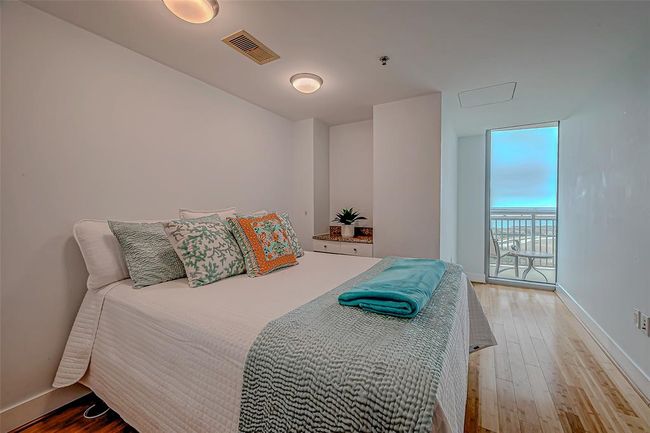 Experience tranquility in this secondary bedroom featuring a built-in desk, elegant bamboo flooring, and stunning bay views. | Image 14
