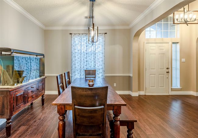 Dining room with a chandelier, arched walkways, dark wood-type flooring, ornamental molding, and a textured ceiling | Image 7