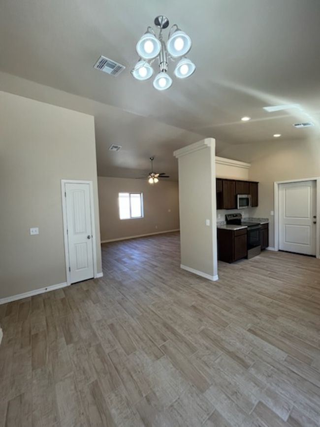 Unfurnished living room featuring a ceiling fan, light wood-style flooring, a chandelier, and baseboards | Image 4