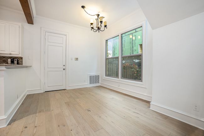 Unfurnished dining area with light wood-style floors, visible vents, baseboards, and an inviting chandelier | Image 4