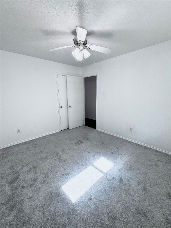 Unfurnished bedroom with a textured ceiling, carpet, and a ceiling fan | Image 24