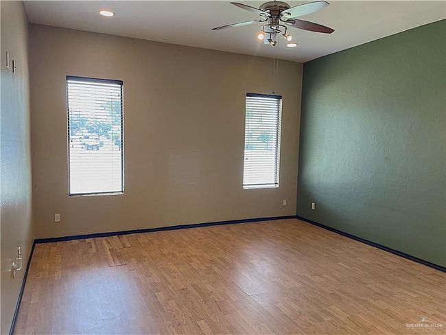 Empty room with wood finished floors, a ceiling fan, baseboards, and recessed lighting | Image 11