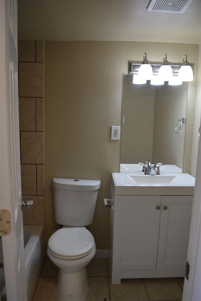 Full bathroom with a bathing tub, toilet, visible vents, vanity, and tile patterned floors | Image 9