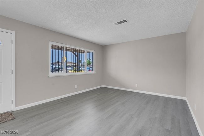 Unfurnished room with baseboards, wood finished floors, visible vents, and a textured ceiling | Image 8