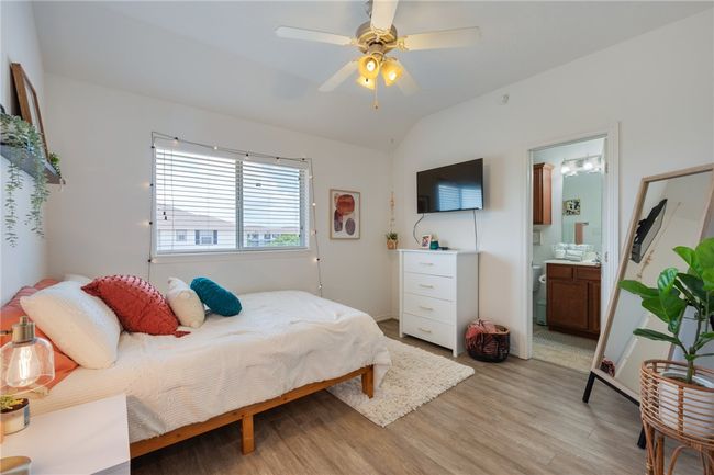 Bedroom featuring light wood-style flooring, lofted ceiling, ensuite bath, and a ceiling fan | Image 15