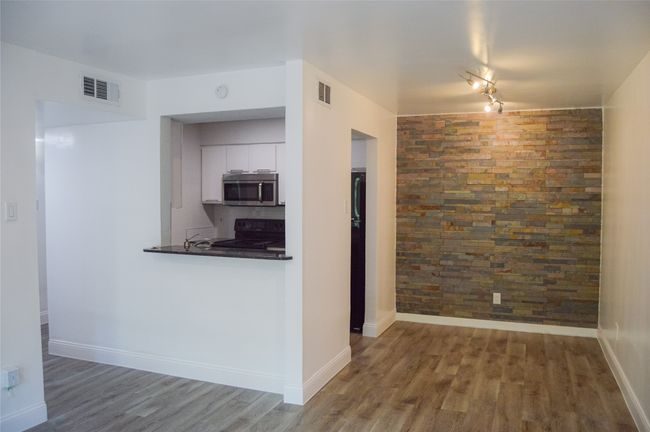 Kitchen featuring stainless steel microwave, black range with electric stovetop, wood finished floors, and white cabinets | Image 12