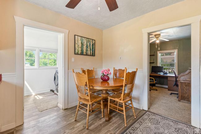Dining space featuring ceiling fan, a textured ceiling, wood finished floors, an office area, and wainscoting | Image 10