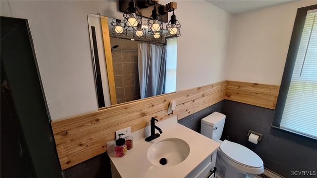Bathroom featuring toilet, wainscoting, a shower with curtain, and vanity | Image 22