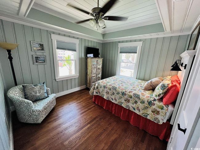 Bedroom with dark wood-type flooring, ceiling fan, ornamental molding, and multiple windows | Image 17