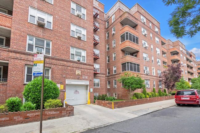 View of apartment building / complex featuring concrete driveway and a garage | Image 16