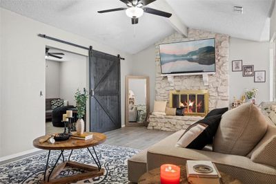 Spacious living area featuring a beautiful stone wood-burning fireplace. | Image 3