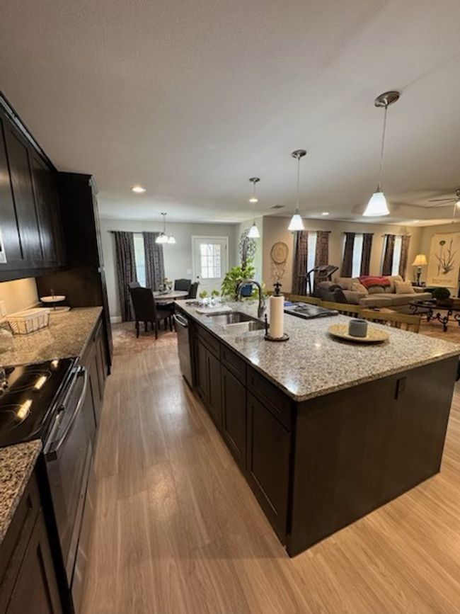 Kitchen featuring light wood finished floors, range with electric stovetop, dishwasher, and a sink | Image 10