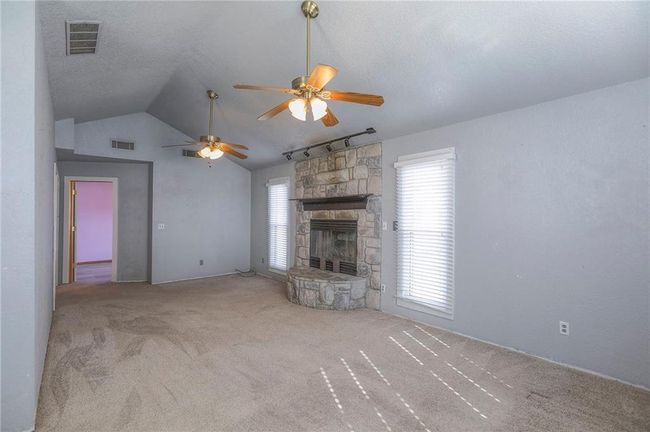 Unfurnished living room with a fireplace, a textured ceiling, visible vents, and a ceiling fan | Image 17