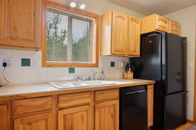 Kitchen with black appliances, light countertops, backsplash, and light brown cabinets | Image 27
