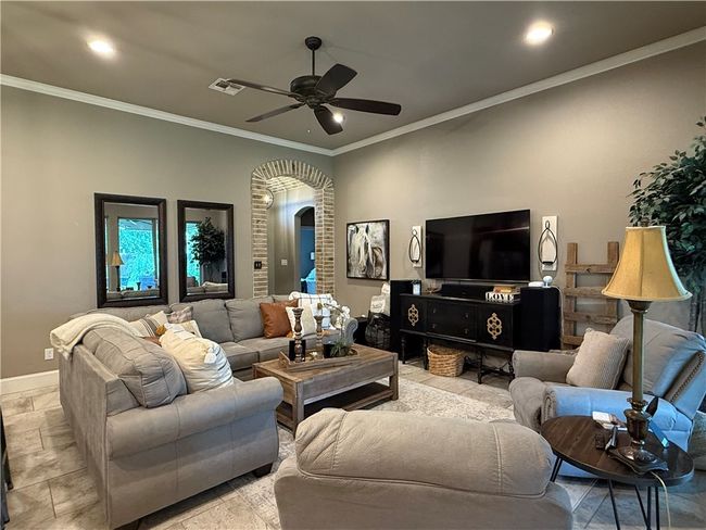 Living room featuring arched walkways, a ceiling fan, crown molding, and recessed lighting | Image 6