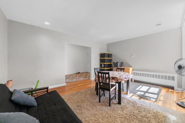 Dining space with radiator, wood finished floors, and baseboards | Image 10
