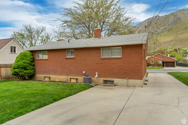 Back of house with a chimney, central AC unit, fence, a yard, and a mountain view | Image 19