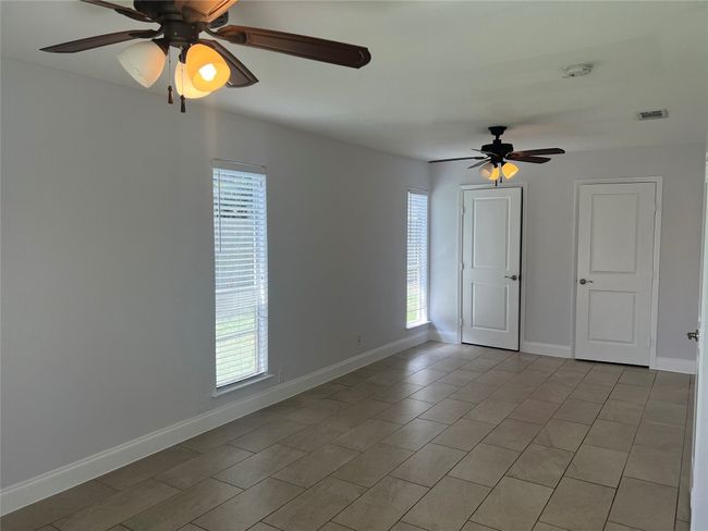 Unfurnished room featuring a ceiling fan, healthy amount of natural light, and light tile patterned flooring | Image 9