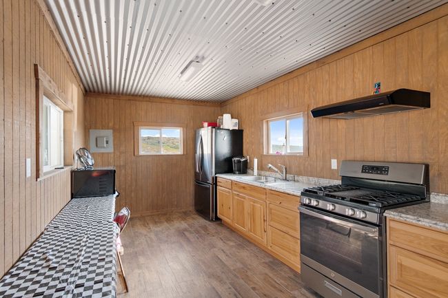 Kitchen with appliances with stainless steel finishes, a wealth of natural light, wooden walls, and range hood | Image 19