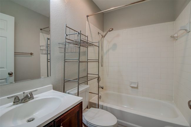 Bathroom featuring toilet, shower / bath combination, vanity, and a textured wall | Image 23