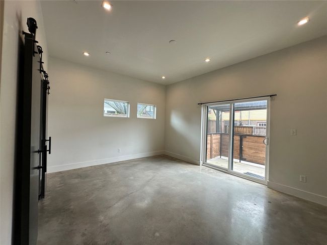 Empty room featuring concrete flooring, a barn door, and recessed lighting | Image 27