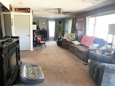 Carpeted living room featuring a textured ceiling and ceiling fan | Image 3