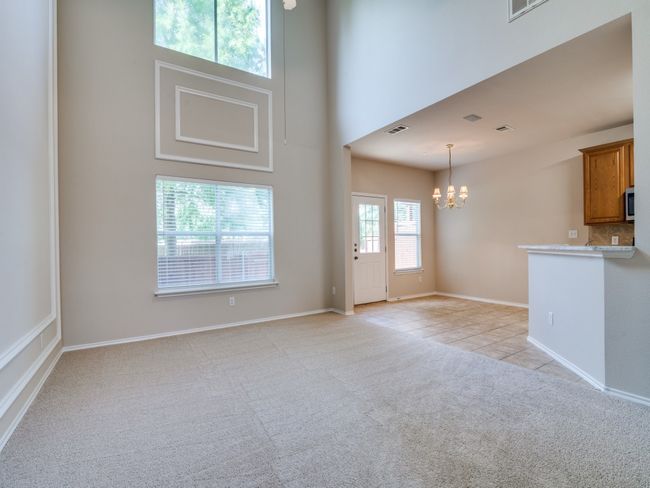 Unfurnished living room featuring a chandelier, light carpet, a high ceiling, and light tile patterned flooring | Image 5