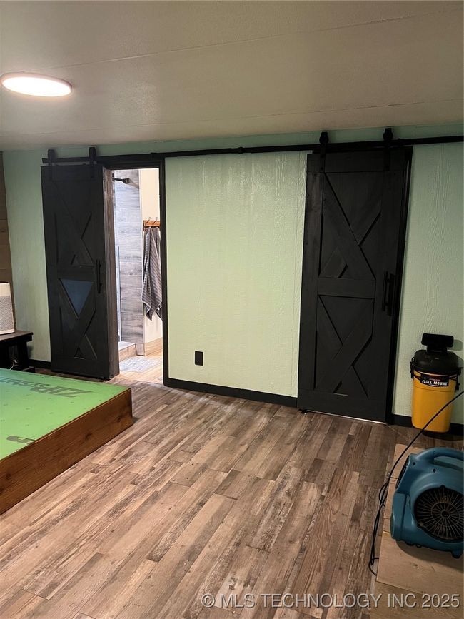 Empty room with a barn door and wood finished floors | Image 11