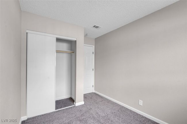 Unfurnished bedroom featuring carpet, visible vents, a closet, baseboards, and a textured ceiling | Image 29