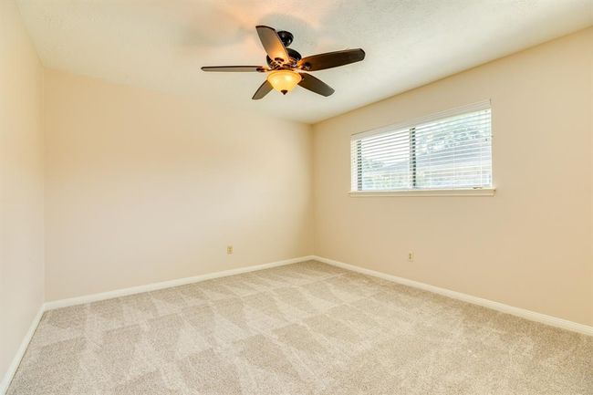 Bedroom 2 at the center of the home with a ceiling fan, walk-in closet and new carpet. | Image 25