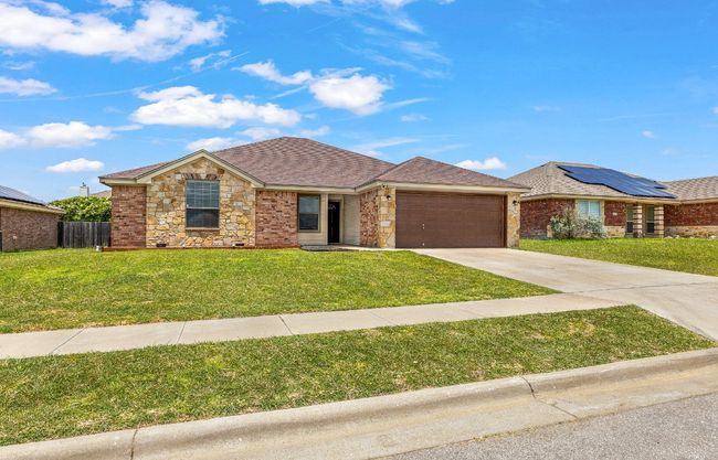 Single story home featuring concrete driveway, an attached garage, a shingled roof, and stone siding | Image 4