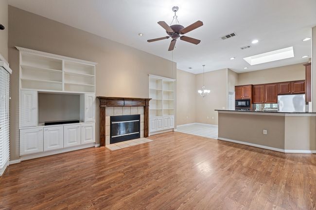 Unfurnished living room with a tile fireplace, a skylight, light wood finished floors, built in shelves, and recessed lighting | Image 25
