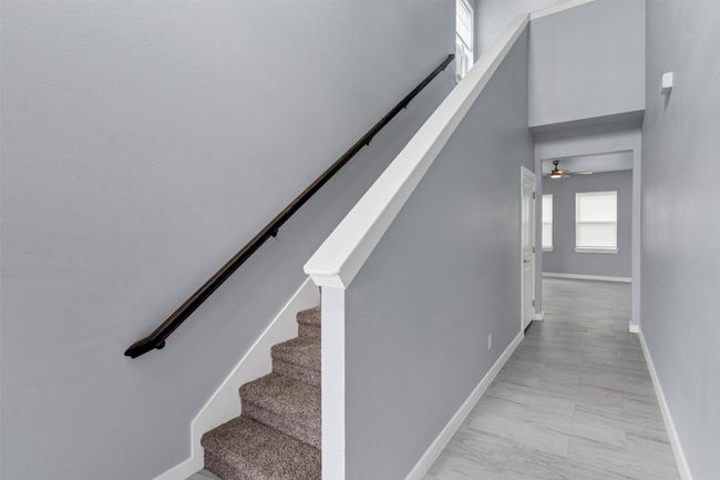Stairs featuring a ceiling fan, marble look tiles, and a towering ceiling | Image 6