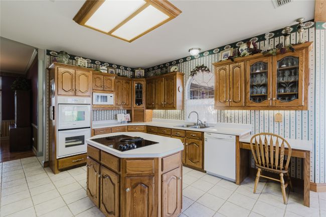 Kitchen featuring light tile patterned flooring, sink, white appliances, and a kitchen island | Image 10