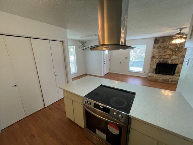 Kitchen featuring wood finished floors, stainless steel electric range, island range hood, a textured ceiling, and healthy amount of natural light | Image 16