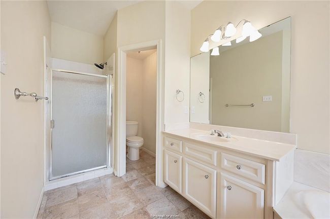 Full bath featuring a shower stall, vanity, toilet, a garden tub, and baseboards | Image 17