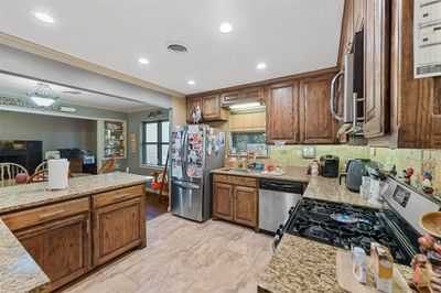 Kitchen with backsplash, sink, crown molding, appliances with stainless steel finishes, and light stone counters | Image 3