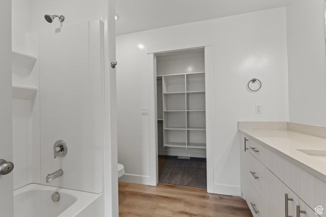 Bathroom with wood finished floors, shower / bathtub combination, toilet, vanity, and baseboards | Image 10