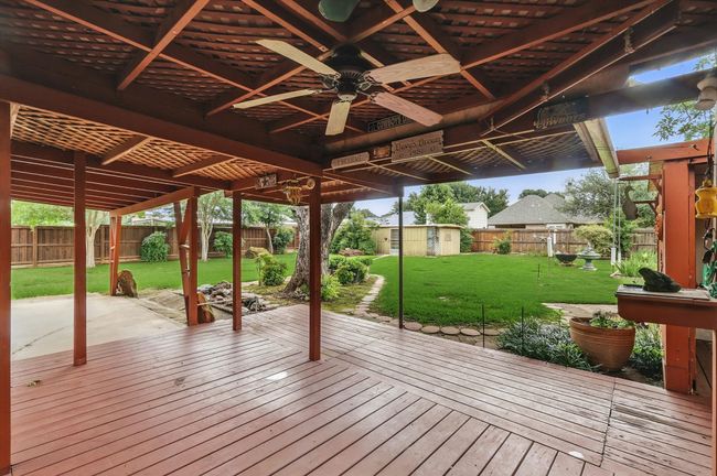 Wooden terrace with a ceiling fan, an outdoor structure, and a patio | Image 10