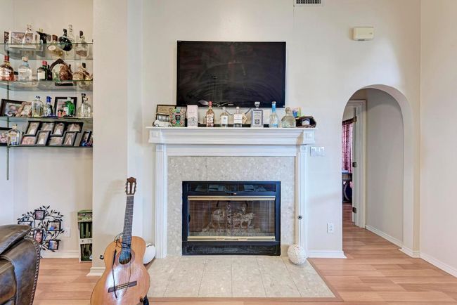 Living area with wood finished floors, arched walkways, a tile fireplace, and baseboards | Image 14
