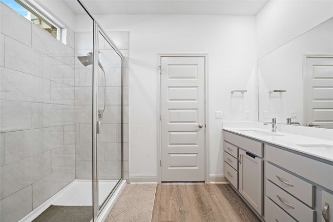 Full bathroom with a sink, baseboards, double vanity, and a stall shower | Image 23