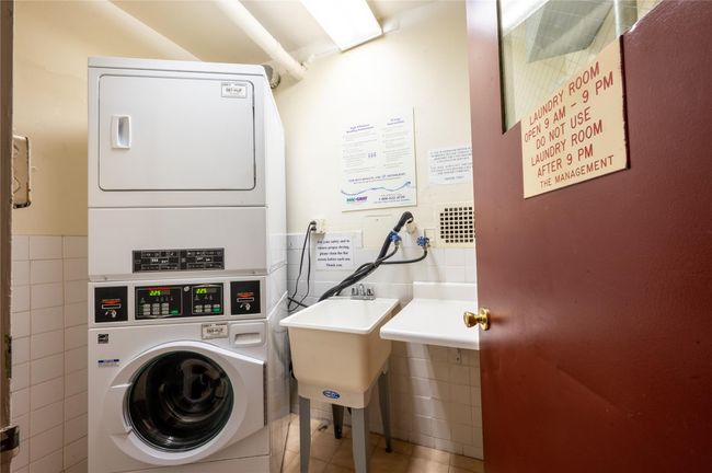 Community laundry room with tile patterned floors, tile walls, wainscoting, and stacked washer / drying machine | Image 15