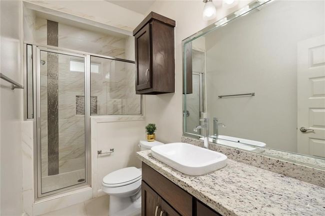 Bathroom with vanity, a shower with shower door, and toilet | Image 9