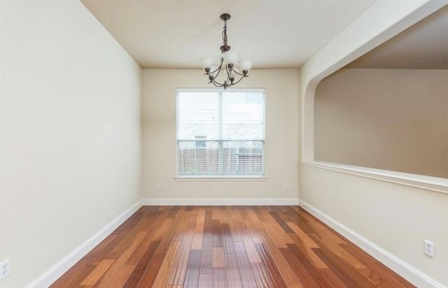Unfurnished dining area featuring a chandelier, wood finished floors, baseboards, and arched walkways | Image 10