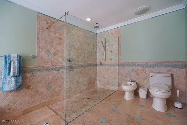 Master bathroom with tile walls, walk in shower, a bidet, crown molding, and tile patterned flooring | Image 21