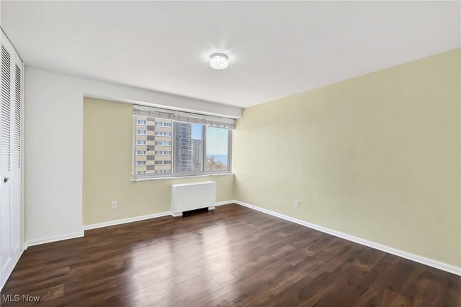 Unfurnished bedroom with radiator, wood finished floors, a closet, and baseboards | Image 16