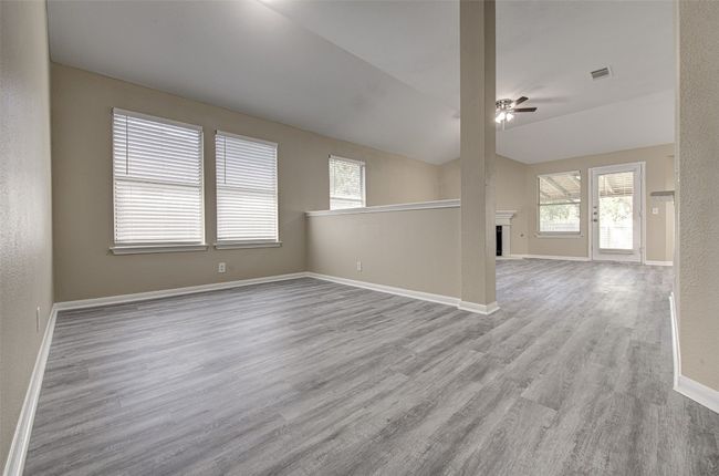 Spare room with ceiling fan, wood finished floors, a fireplace, and lofted ceiling | Image 9