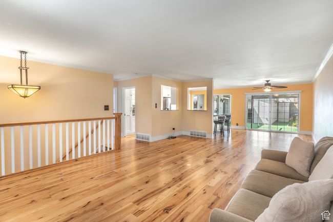 Living area featuring ceiling fan, visible vents, light wood finished floors, and ornamental molding | Image 5