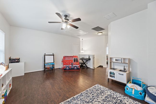 Rec room with attic access, a ceiling fan, and wood finished floors | Image 25